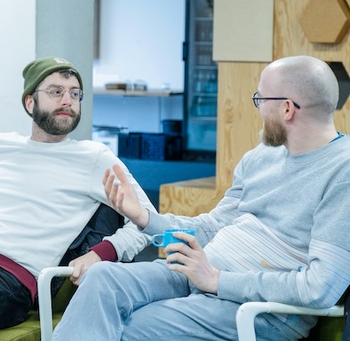 Two team members sitting at a table and talking to each other.